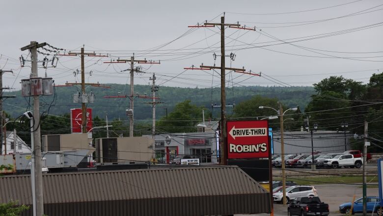 Power poles can be seen in a town with a Robin's drive thru sign, cars and the tops of buildings visible. 