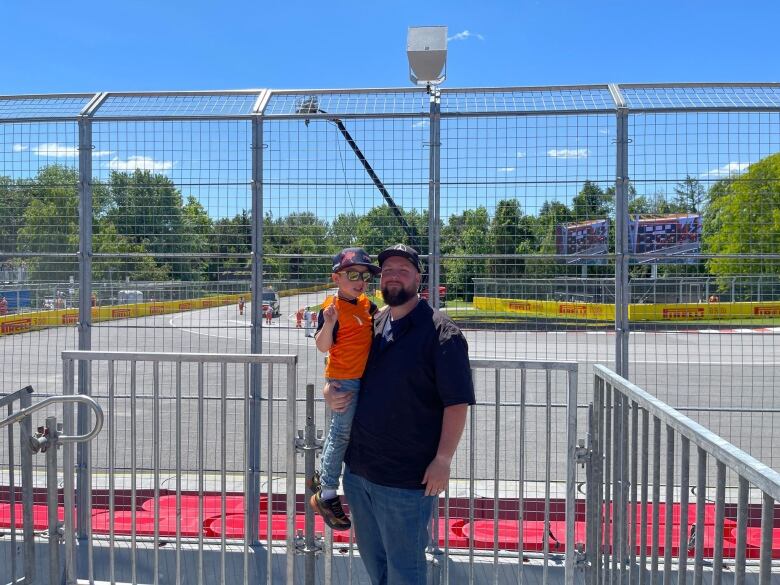 man with kid in front of racetrack. 