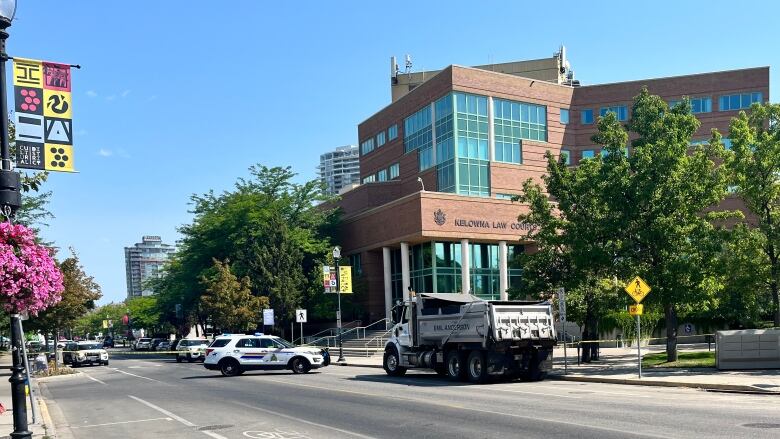 Several police cars are parked around a building with tapes around the cordoned off area.