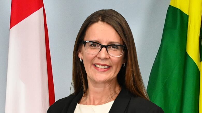 A middle-aged woman with long brown hair and dark-rimmed glasses wears a black blazer and white shirt for an official city portrait.