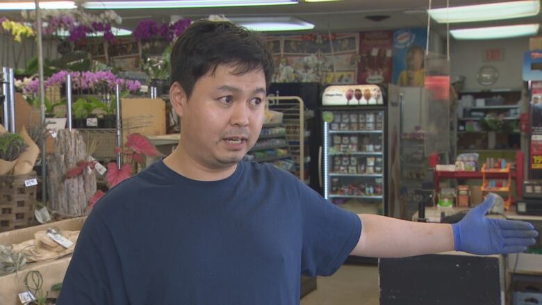 A man with brown hair stands in a flower shop.