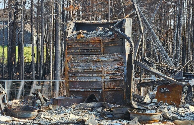 A large, charred tool chest is seen amid burned rubble of a home.