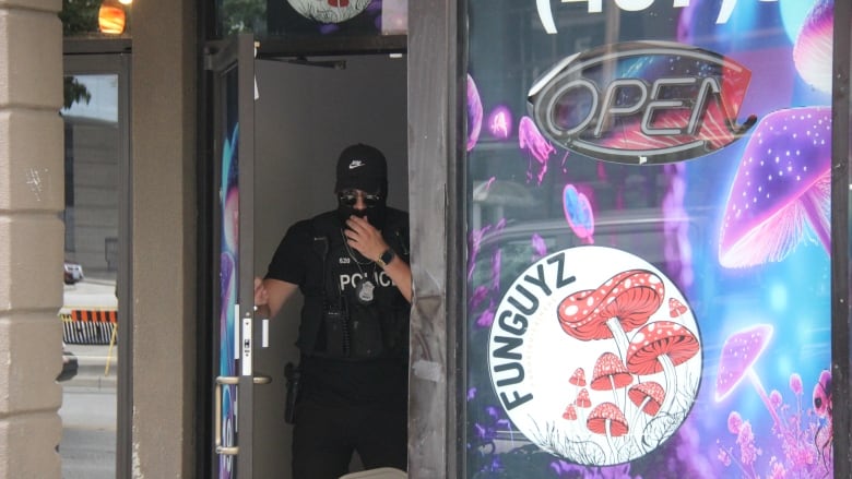 A masked police officer coming out of a store.