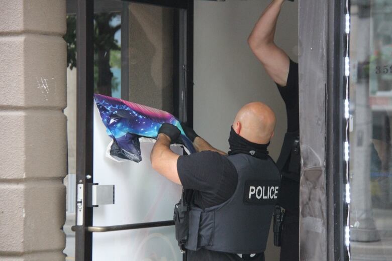 Police officer removing a sign from a door.