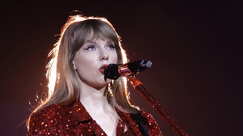 Taylor Swift performs on stage holding a guitar.