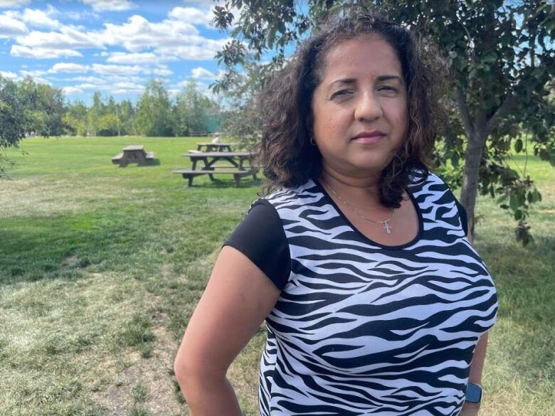 A woman standing outside in a shirt with a wavy black and white pattern.