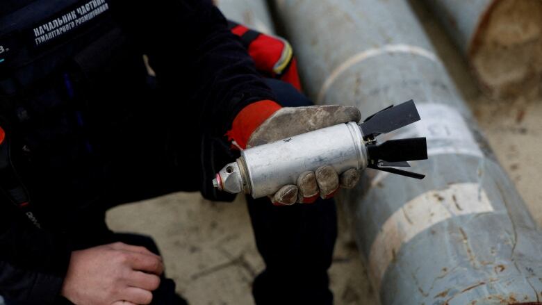 A person's hands are shown holding a small metallic weapon.