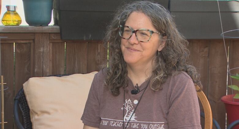 A woman sits on a backyard deck.