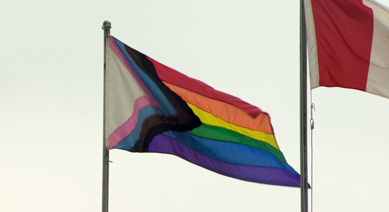 A rainbow pride flag blows in the wind.