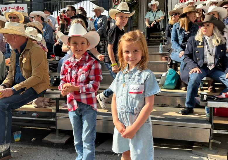 a boy and girl, about 5, wearing western wear pose for a picture 