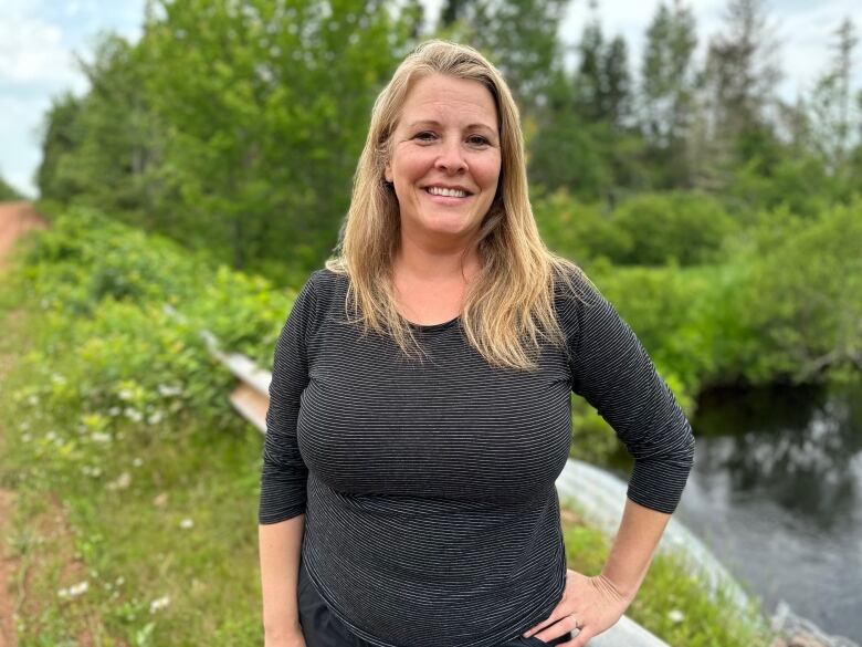 A woman stands near a stream 