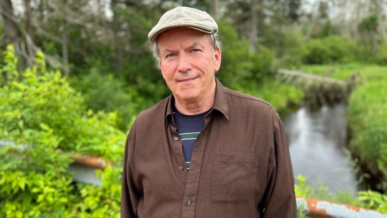 a man in a cap stands near a stream 