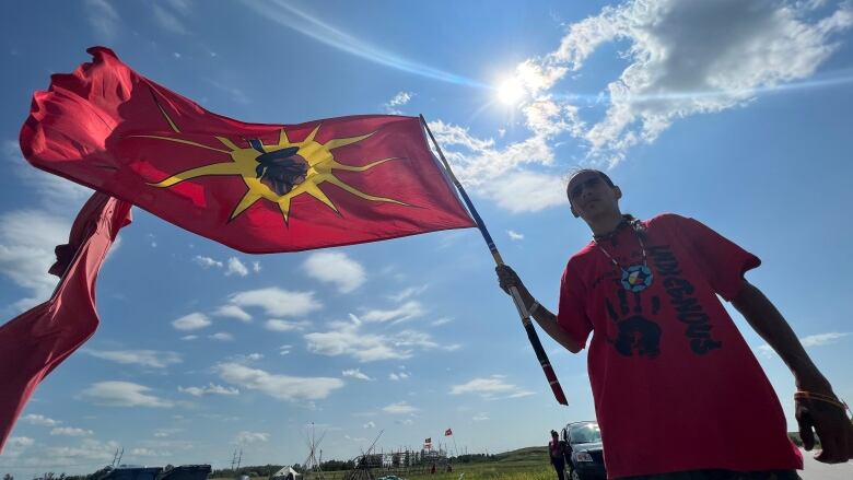 A man in a red shirt holds up a flag.