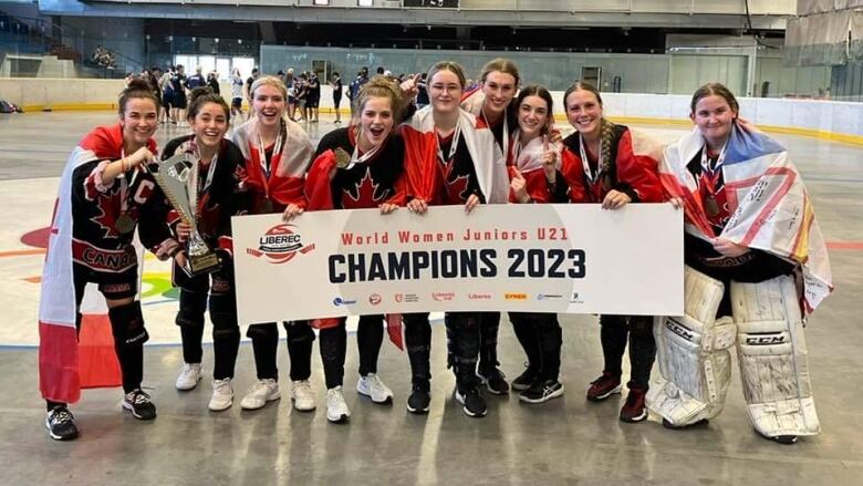 Nine young women in jerseys smile behind a banner that reads 