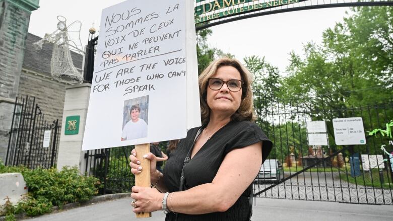 Nancy Babalis holds a sign and picture of her son Peter Kitsos during a protest outside Notre-Dame-des-Neiges Cemetery in Montreal, Sunday, July 9, 2023.