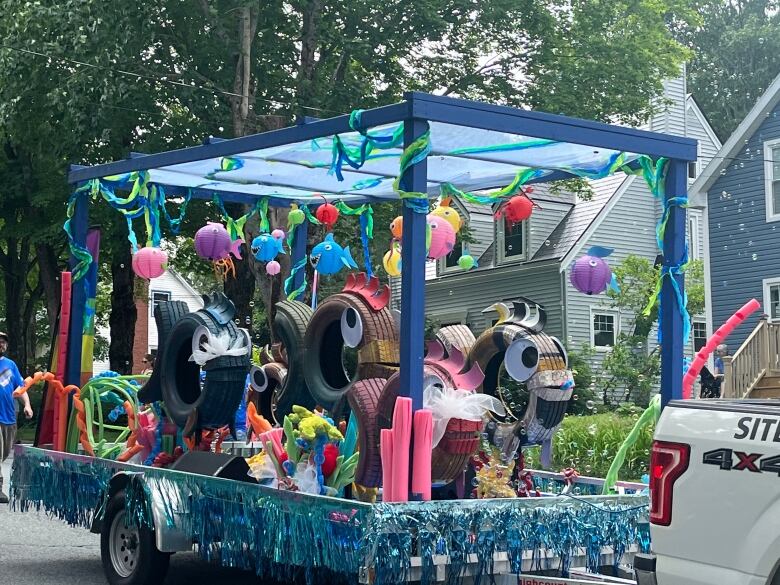 A float filled with tires and googly eyes is decorated with balloons.