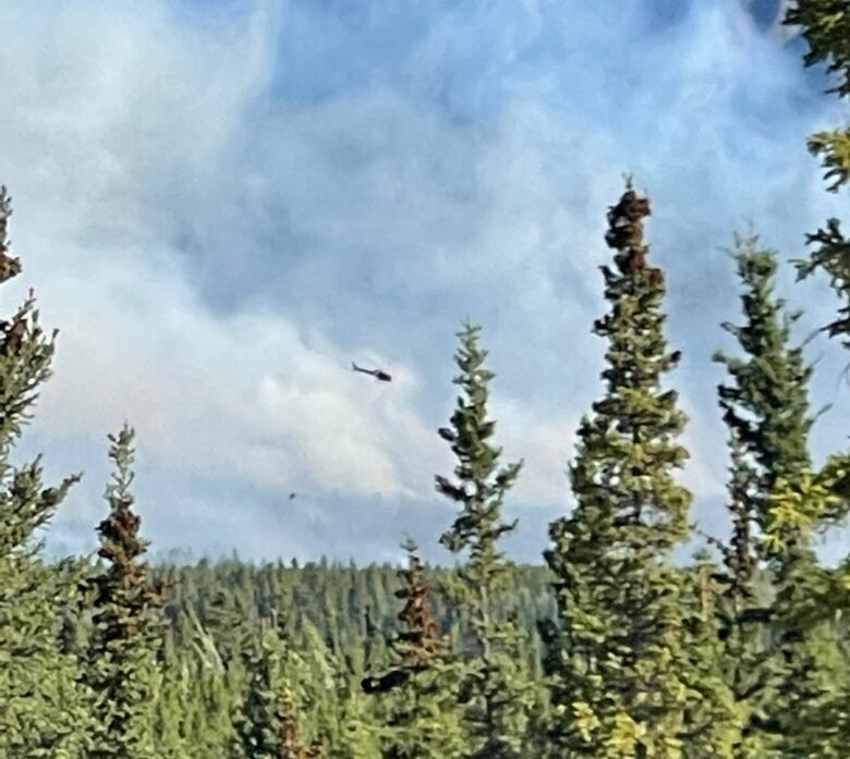 A helicopter flying through wildfire smoke