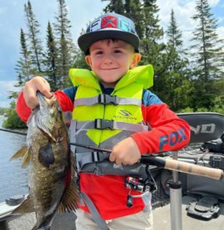 A young boy holds a fish he caught. 