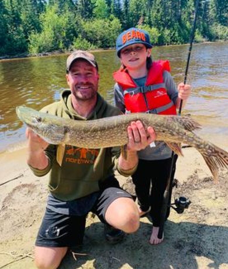 A father and son hold a fish in their hands. 