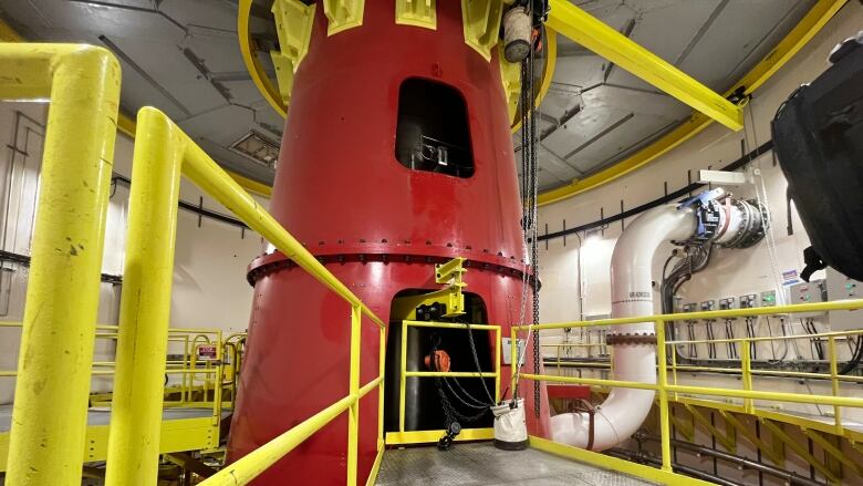 A red cylindrical metal tube connects the generator, spining above, and the turbine, spinning below, inside unit 1 of the Muskrat Falls power plant.