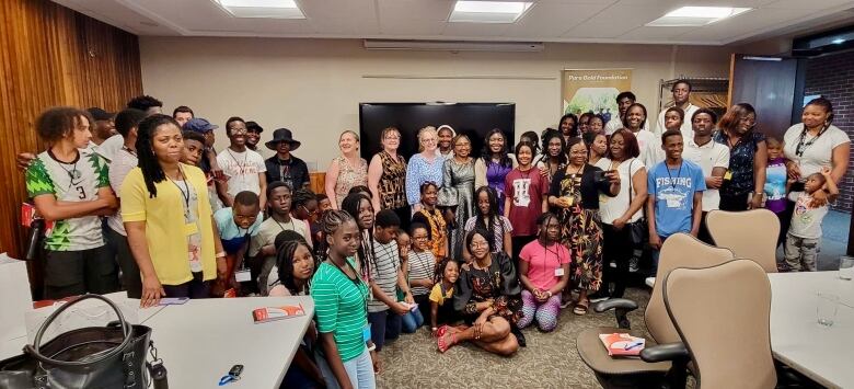 A group of children and adults in a classroom. Some squatting and other standing for a photograph.