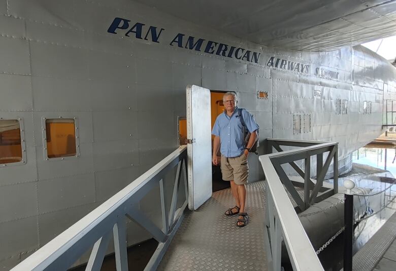 A man standing on a ramp outside of a large grey structure with blue lettering that reads 