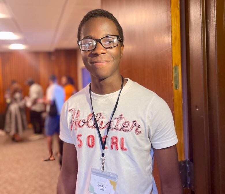 A teenager boy standing in front of the entrance of a conference room.