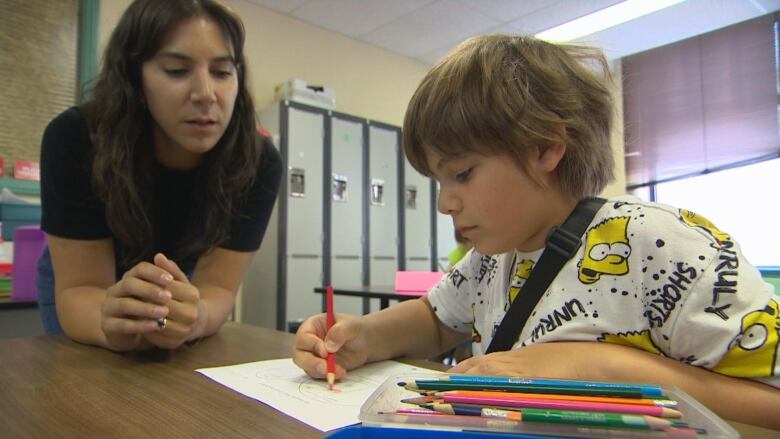 Girl on left supervising a boy's school work. 