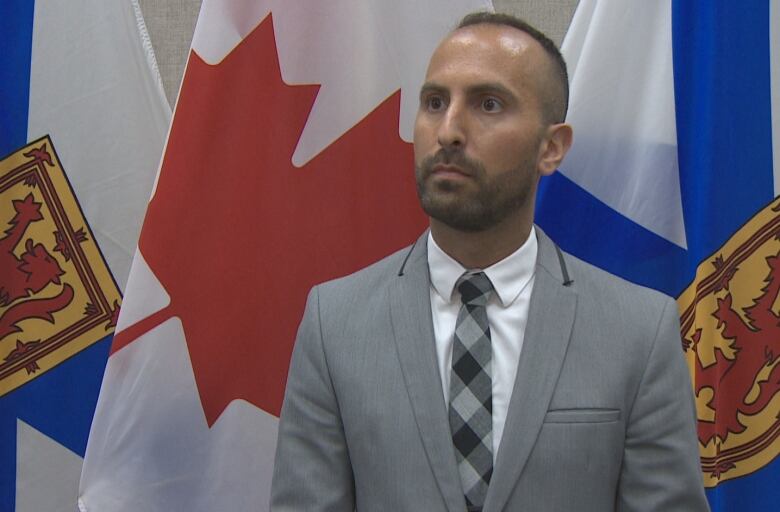 A man stands in front of flags.