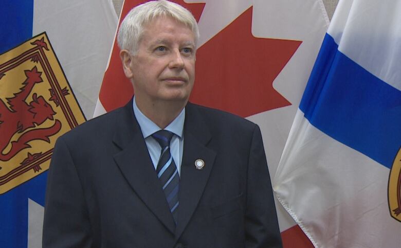 A man stands in front of flags.