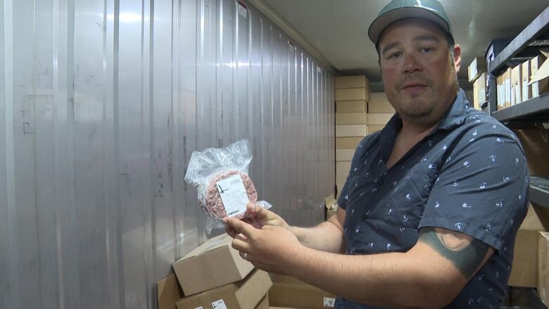 A man holds up a small package of meat. 