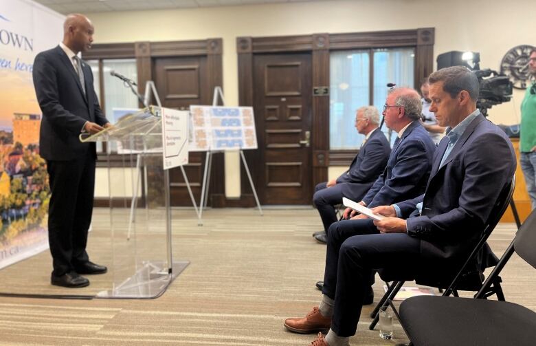 Housing Minister Ahmed Hussen at lectern with Charlottetown MP Sean Casey, Charlottetown Mayor Philip Brown, and provincial Housing Minister Rob Lantz in front row.