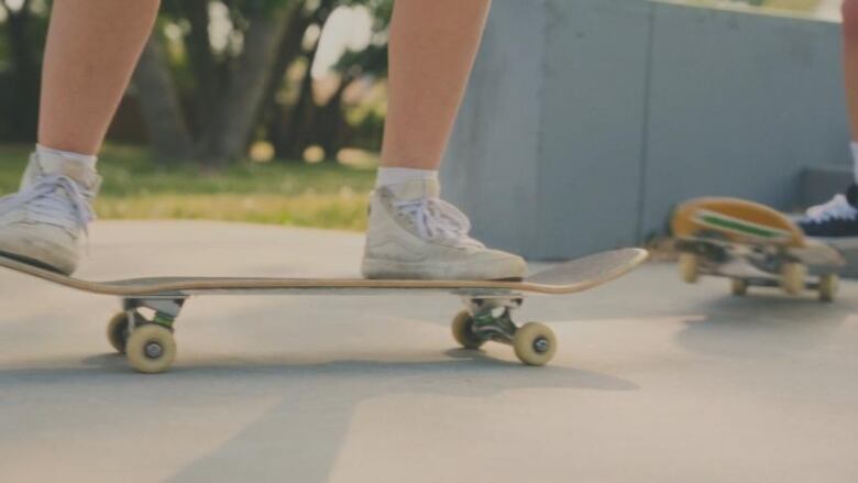 The legs and feet of a skateboarder on their board.