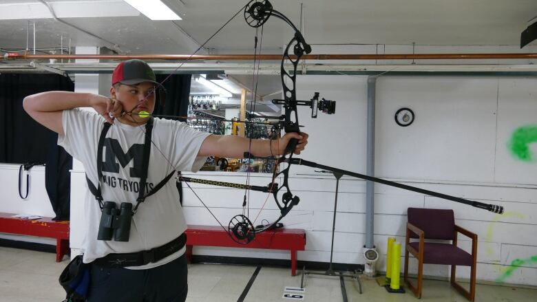 A young Mtis boy pulls the arrow back in his bow in an indoor shooting range.