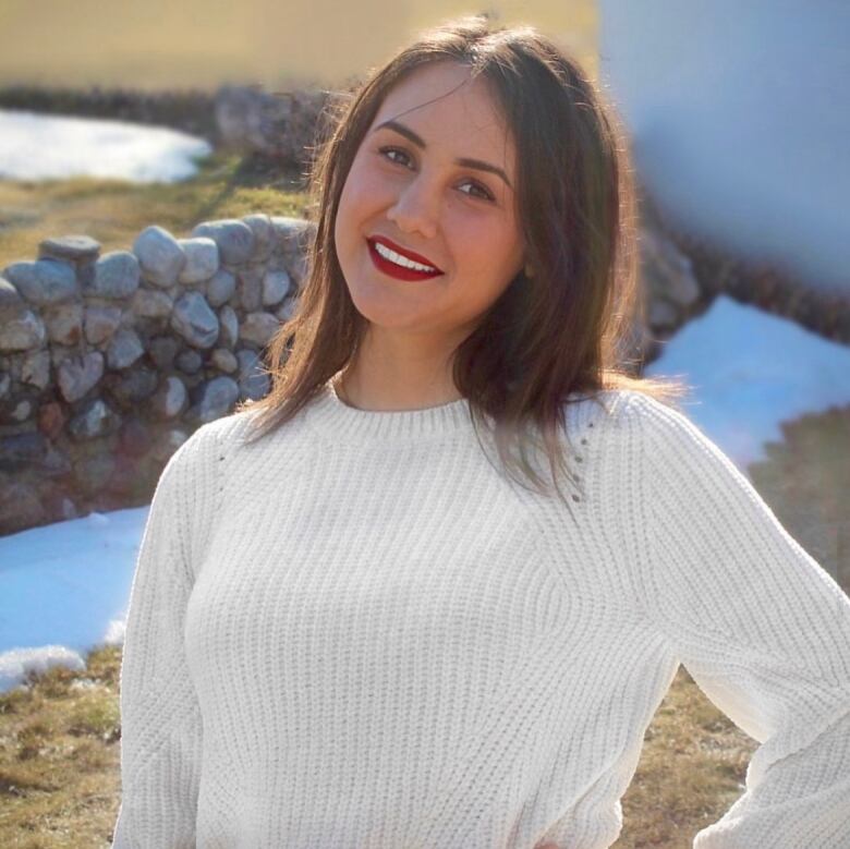 A girl with mid-length brown hair in a long sleeve white shirt