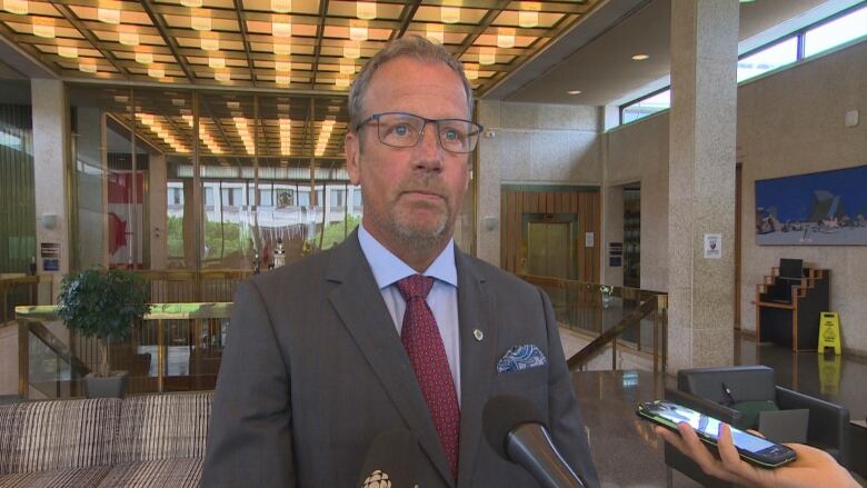 A man in a suit and glasses standing in a foyer at city hall.