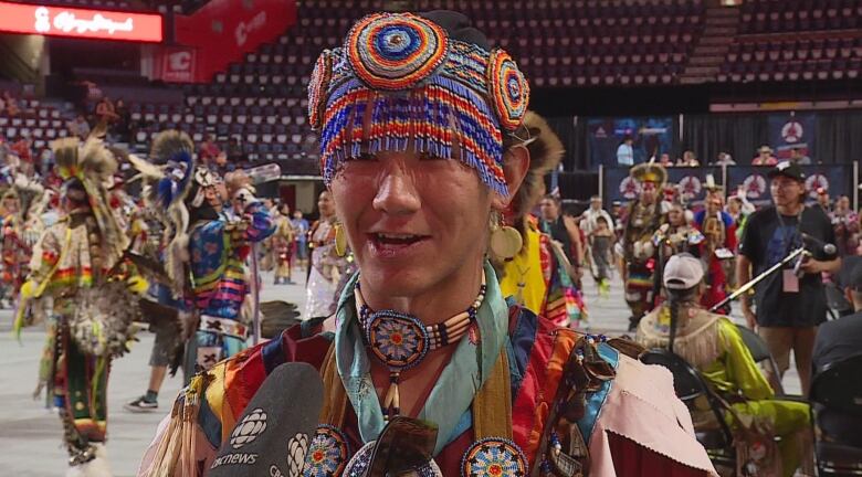 A man dressed in a colorful outfit is seen flaunting striking head gear and accessories.