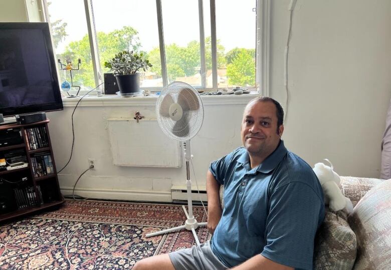 Gregory Walton sitting on his living room couch. 