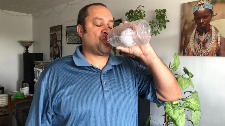 Gregory Walton takes a much-needed sip of ice water, one of his methods to stay cool in his fifth floor apartment. 