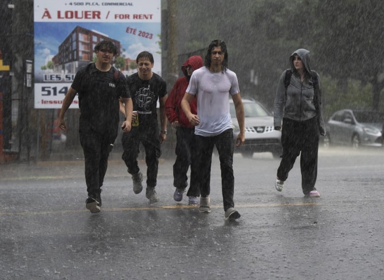 Pedestrians walk through a rainstorm Thursday, July 13, 2023  in Montreal.