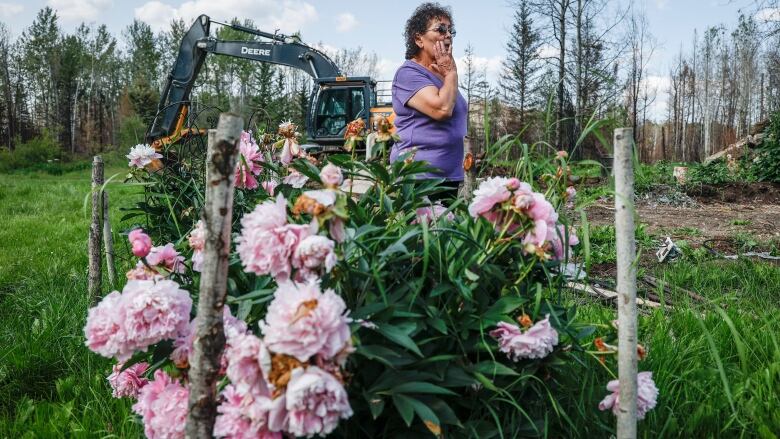 A woman stands behind a bunch of flowers. 