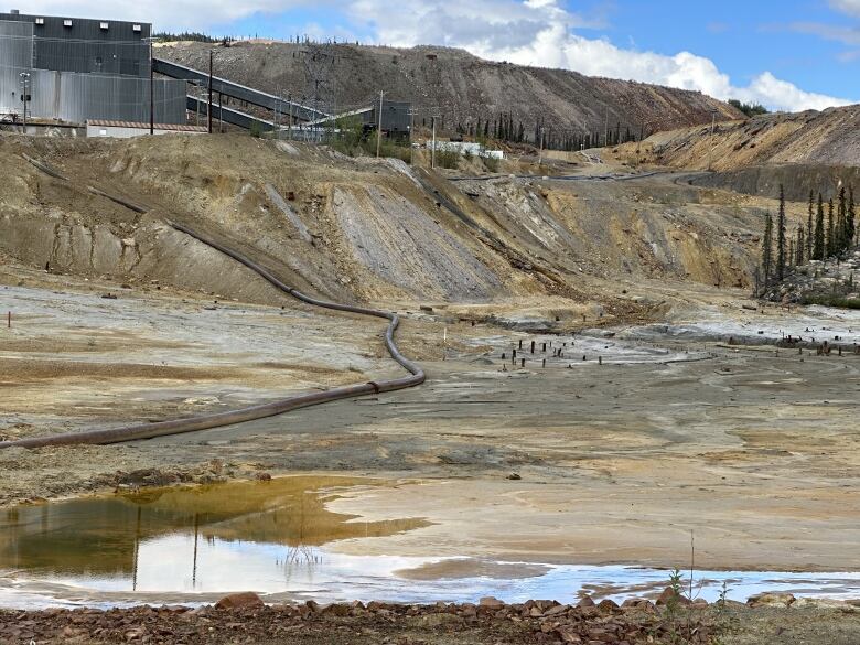 A view of an abandoned mine site with a milling facility visible on a hill.