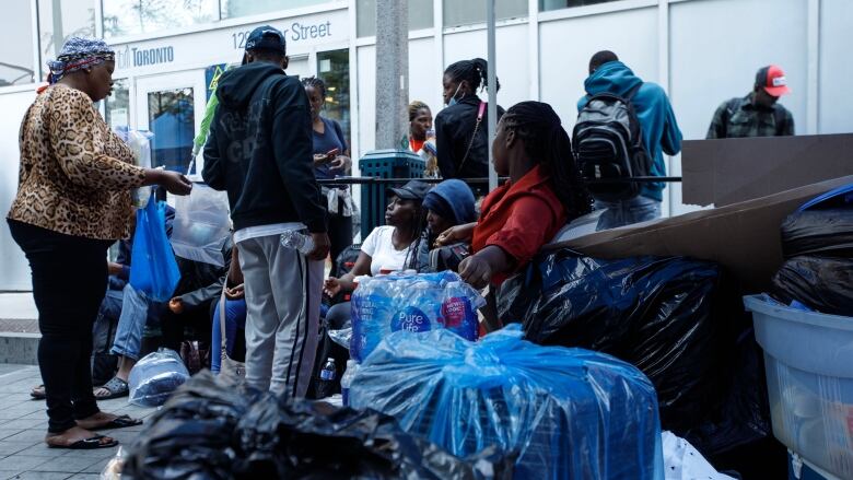 Asylum seekers from Africa and other locales are seen outside of a shelter intake office at Peter St. and Richmond St. in Toronto, on July 14, 2023.