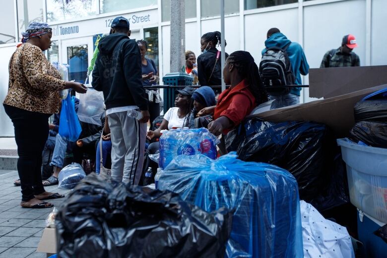 Asylum seekers from Africa and other locales are seen outside of a shelter intake office at Peter St. and Richmond St. in Toronto, on July 14, 2023.