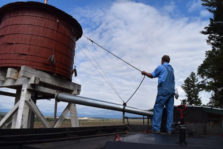 Gene Roshau, engineer for Fort Steele's 1077 steam locomotive, is seen putting water into the train on Tuesday, July 11, 2023. 