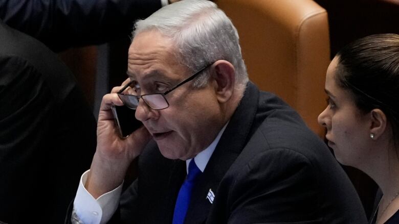 Israeli Prime Minister Benjamin Netanyahu is seen using a mobile phone while seated in the Knesset, the Israeli parliament.