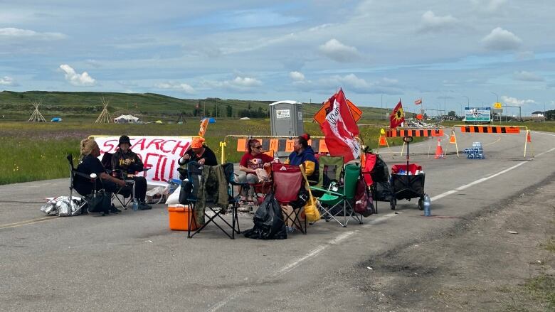 A group of people sit at a blockade 