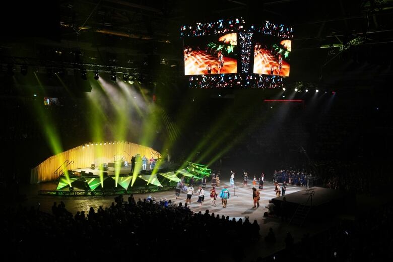 Colourful lights illuminate a stage as people perform a dance.