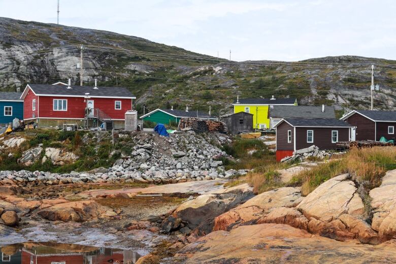 Colourful homes sit on top of rocks and grass.