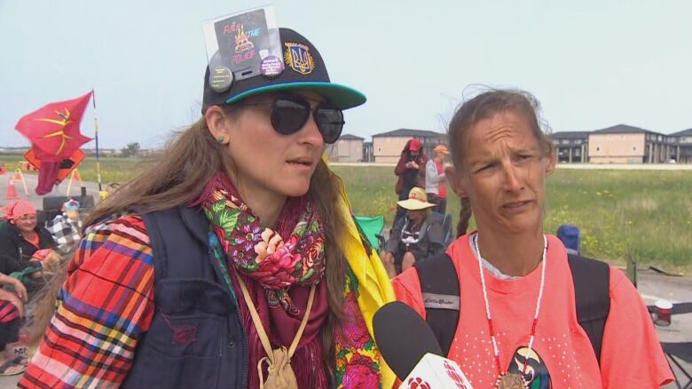 Two women stand side-by-side at an outdoor protest.